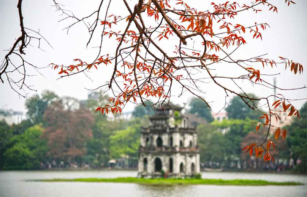 Hồ Gươm lung linh trong ánh nắng sớm mai, với Tháp Rùa cổ kính in bóng nước và cầu Thê Húc đỏ son uốn cong mềm mại. (Ảnh: Sưu tầm internet)