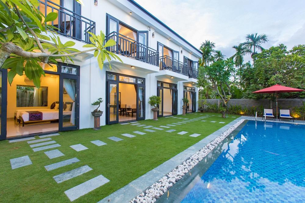 Bãi cỏ xanh mướt bên cạnh hồ bơi ngoài trời tại Hoi An Hideaway Villa