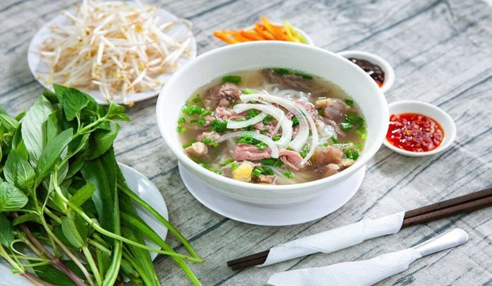 Tô phở đầy đặn, thịt nhiều, ăn kèm với chanh, ớt, rau thơm và hành tươi (Ảnh: Sưu tầm Internet)